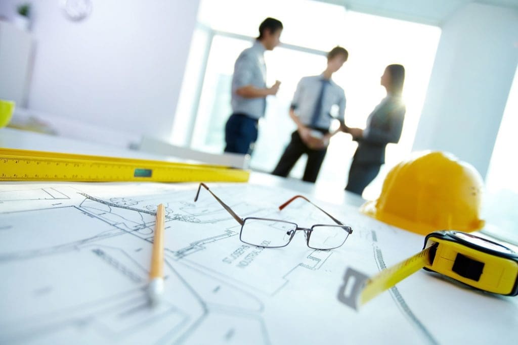 Engineering drawings, hard hat and drafting tools on a desk during project planning